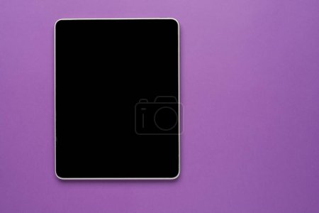 Top view of tablet on the violet pastel color background