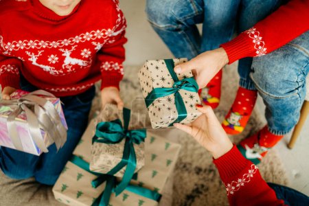 Primer plano de una familia de cuatro personas que celebra la Navidad, intercambiando regalos. Dar regalos en Nochebuena, Feliz Año Nuevo en casa.