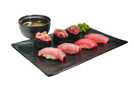 Téléchargez les photos : Différents types de sushis servis sur un plat rectangulaire noir avec soupe de soja japonaise - en image libre de droit