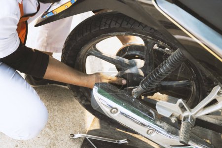 Foto de Trabajador de servicio que cambia la instalación de neumáticos de motocicleta en el taller para la reparación de motocicletas con enfoque suave y luz de fondo - Imagen libre de derechos