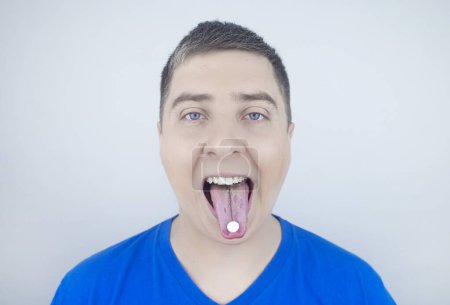 Téléchargez les photos : Probiotiques oraux. Un homme met une pilule avec des bactéries bénéfiques sur sa langue. Dysbactériose et déséquilibre des micro-organismes bénéfiques et nocifs dans la bouche. Augmenter l'immunité et améliorer la santé. - en image libre de droit