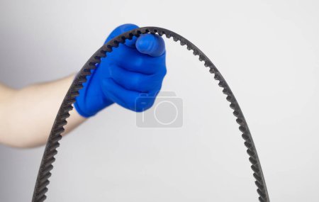 Photo for Timing belt cracked. Replacing a failed engine transmission belt. Cracks in rubber and risk of broken cords. Replacement of equipment according to the regulations. Mechanic in blue gloves - Royalty Free Image