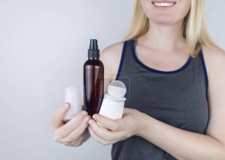 Foto de Girl holds in her hands three eco-friendly antiperspirants with natural ingredients. Refusal of antiperspirants containing toxic substances. Freedom from Aluminum chlorohydrate, alcohol, parabens - Imagen libre de derechos