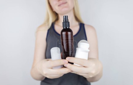 Téléchargez les photos : Girl holds in her hands three eco-friendly antiperspirants with natural ingredients. Refusal of antiperspirants containing toxic substances. Freedom from Aluminum chlorohydrate, alcohol, parabens - en image libre de droit