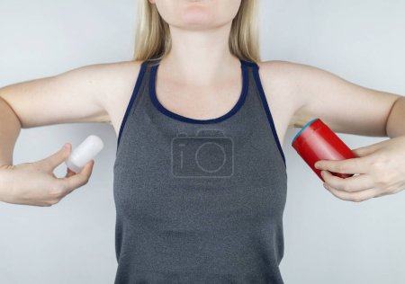 Foto de Left or right. Girl chooses between eco-friendly deodorant without toxins and antiperspirant with toxic elements. In left hand Mineral alum crystal stick, in right hand classic remedy chemical nature - Imagen libre de derechos