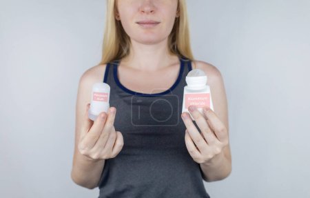 Foto de Left or right. Girl chooses between eco-friendly deodorant without toxins and antiperspirant with toxic elements. In left hand Mineral alum crystal stick, in right hand classic remedy chemical nature - Imagen libre de derechos