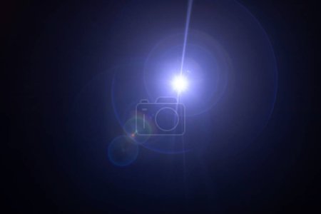 Téléchargez les photos : Éblouissement sur un fond noir. Une caméra pointée vers la lumière produit un effet de torche spécial. Un rayon de soleil et un spectre de couleurs arc-en-ciel. Shimmers et gradients. Illusion optique - en image libre de droit
