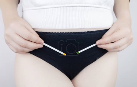 Photo for Bacterial Vaginosis. Vaginal pH. Girl shows sticks for measuring acid-base balance of genital organs. Self-diagnosis. Normal acidity level shown in colors and must be compared with the standard - Royalty Free Image