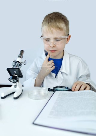 Kinderchemiker. Der Lehrer zeigt ein visuelles Experiment. Ein wissenschaftlicher Mentor vermittelt einen experimentellen Ansatz. Mikroskop, Petrischale, Pipetten, Bücher. Praktische Arbeit in Chemie oder Physik. Laborarbeiten