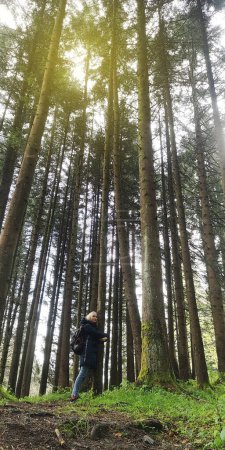 Forest therapy. A girl stands near a tree doing breathing practice and mentally talking to nature. Communication with the coniferous forest and unity with nature