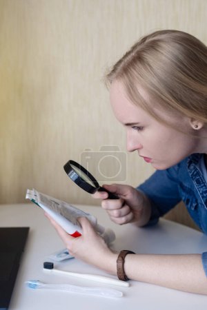 Photo for Toothpaste ingredients. Girl at laptop checks composition of toothpaste and is surprised by dangerous composition of product. Emulsifiers, preservatives, dyes, PEG, SLS, parabens, diethanolamine - Royalty Free Image