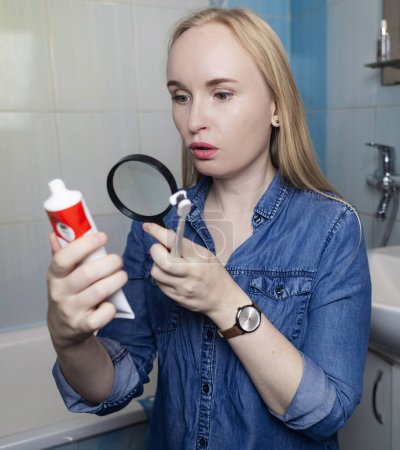 Photo for Toothpaste ingredients. Girl checks composition of toothpaste and is surprised by dangerous composition of product. Emulsifiers, preservatives, dyes, PEG, SLS, parabens, diethanolamine - Royalty Free Image