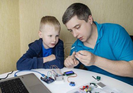 Programming for children. A teacher teaches a child at a robotics and IT school. Boy learning to code control board