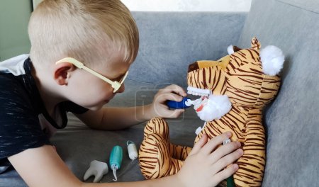 Un garçon se brosse les dents avec un jouet à mâchoire artificielle. Jouer en tant que dentiste, préparation professionnelle d'un enfant pour la profession de dentiste pédiatrique. Hygiène et soins dentaires