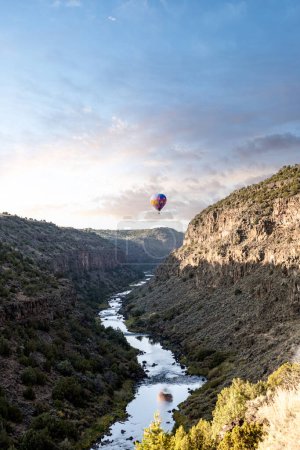 Foto de A colorful hot air balloon floating above the Rio Grande Gorge in Arroyo Hondo, Taos County, New Mexico at sunrise. - Imagen libre de derechos