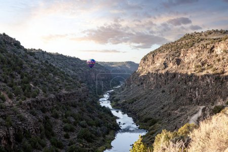Foto de A colorful hot air balloon floating inside the Rio Grande Gorge in Arroyo Hondo, Taos County, New Mexico at sunrise. - Imagen libre de derechos