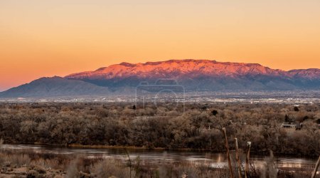 Albuquerque, New Mexico at sunset with Rio Grande in the front and the Sandia Mountains in the background.