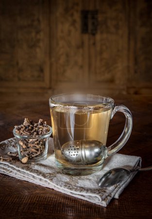 Foto de Taza de té caliente de yerba mansa con un poco de raíz seca en una mesa - Imagen libre de derechos