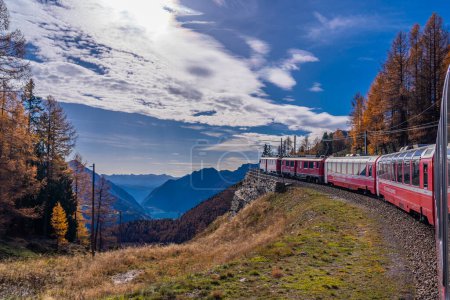 Foto de ALP GRUEM, SUIZA - 28 DE OCTUBRE DE 2022: Bernina Express de la línea ferroviaria de Rhaetian en un día de otoño subiendo la montaña - Imagen libre de derechos