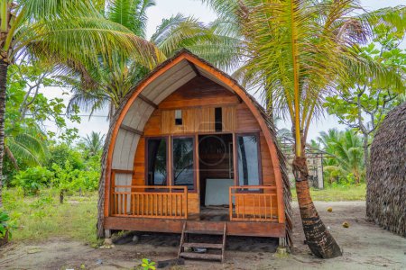 Small traditionally built bamboo huts among palm trees on Fam Island, Raja Ampat, Indonesia