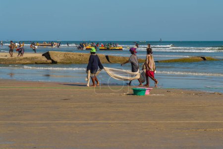 Téléchargez les photos : Morondava, Madagascar - May 31.2023: Three women at the coastline from Morondava walking with a fishnet - en image libre de droit