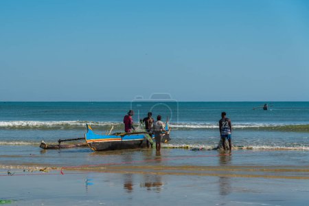 Téléchargez les photos : Morondava, Madagascar - May 31.2023: Malagasy man at the coastline from Morondava with a boat fishing - en image libre de droit