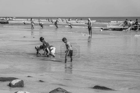 Téléchargez les photos : Morondava, Madagascar - May 31.2023: Children at the coastline from Morondava during low tide, black white - en image libre de droit