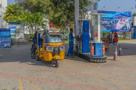 Téléchargez les photos : Puttaparthi, Inde - 10 décembre 2023 : pousse-pousse automatique à une station-service avec le conducteur et le préposé à la station-service - en image libre de droit