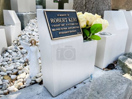 Téléchargez les photos : Sydney, Australie - 27 janvier 2024 : Au cimetière, une statue d'ange veille, à côté d'une plaque de crémation avec dévouement. Des roses blanches ornent, un hommage serein aux souvenirs chéris. - en image libre de droit