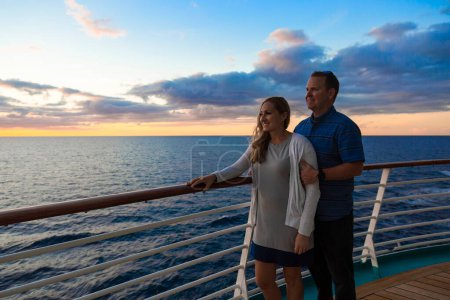 Téléchargez les photos : Joli couple d'âge moyen profitant de la vue sur le coucher du soleil depuis le pont d'un bateau de croisière pendant des vacances romantiques ensemble - en image libre de droit