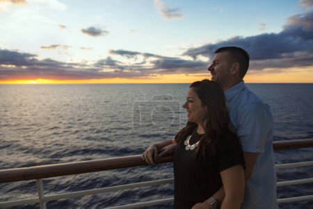 Photo for Attractive middle-aged couple enjoying the sunset view from the deck of a cruise ship while on a romantic vacation together - Royalty Free Image