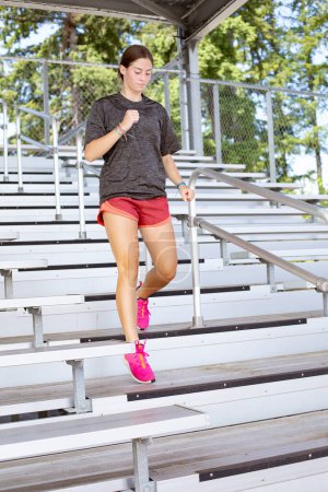 Photo for Young Woman running up and down bleacher stairs at a stadium training for her high school sports season. Young woman working to stay fit and healthy. - Royalty Free Image