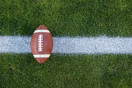 Téléchargez les photos : Vue d'en haut d'un football américain assis sur un terrain de football en herbe sur la ligne de cour. Image générique de Sports. Beaucoup d'espace de copie - en image libre de droit