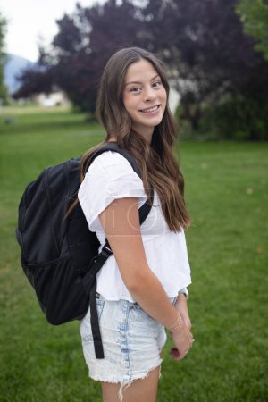 Foto de Hispanic Teenage Girl Portrait. Una hermosa chica latina sonriendo antes de ir a la escuela con una mochila al aire libre. Estudiante de secundaria concepto foto - Imagen libre de derechos