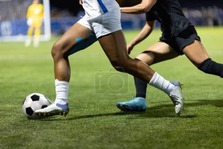 Foto de Sección recortada de dos jóvenes jugadores de fútbol masculino corriendo en el estadio de fútbol. Ángulo bajo - Imagen libre de derechos