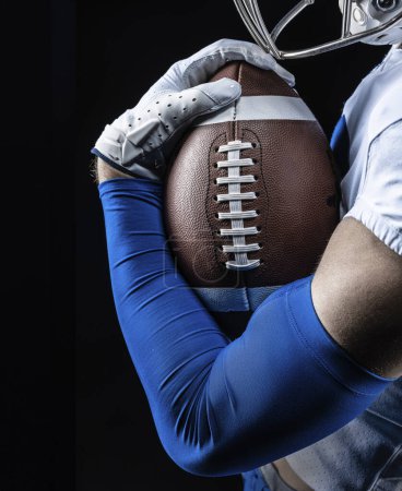 Photo for Close up studio photo of an American Football player holding tightly onto a football. Good generic American Football photo - Royalty Free Image