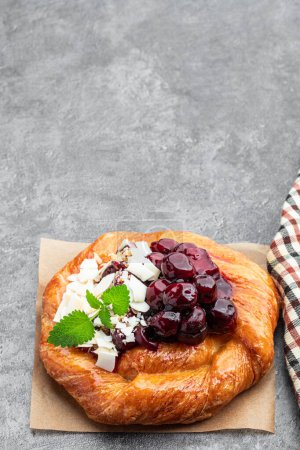 Homemade  cherry puff pastry bun on gray background 
