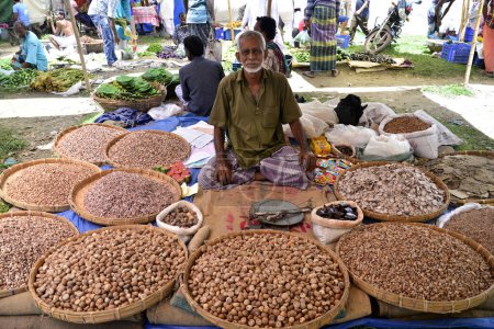 Photo for A shopkeeper waiting for customers to sale betel nut at Kaikkarateke weekly market, Narayanganj district in Bangladesh, On June 21, 2015 - Royalty Free Image