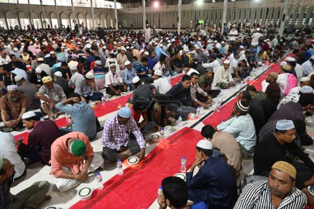 Téléchargez les photos : Les dévots musulmans s'assoient ensemble avant de rompre leur jeûne pendant le mois sacré du Ramadan à la mosquée nationale Baitul Mukarram à Dacca, Bangladesh, le 13 mars 202 - en image libre de droit