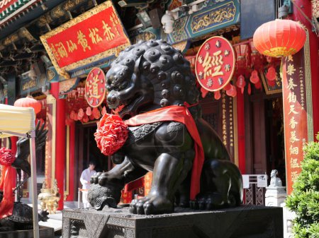 Photo for November 13, 2023. Wong Tai Sin Temple - Wong Tai Sin area, Hong Kong. Black color statue of lion dog in front of Wong Tai Sin temple's main building. - Royalty Free Image