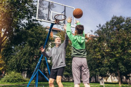 Homme mûr jouant au basket avec son fils