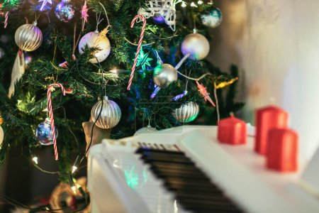 Foto de Piano con velas rojas colocado junto a un árbol de Navidad decorado. - Imagen libre de derechos