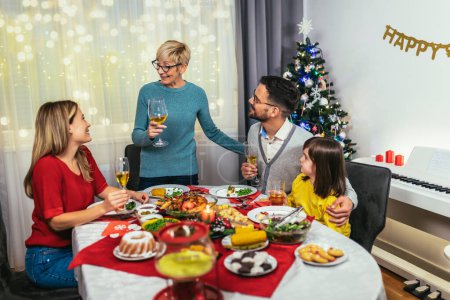 Photo for Photo captures the warmth and joy of a Christmas dinner with a beloved grandmother, mother, father, and daughter. The family is gathered around the festive table, smiling and laughing as they enjoy a traditional feast of turkey, stuffing, and all the - Royalty Free Image