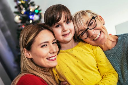 Téléchargez les photos : Grand-mère, fille et petite-fille célébrant Noël ensemble dans la joie - en image libre de droit