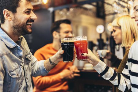 Photo for Smiling young friends drinking craft beer in pub - Royalty Free Image
