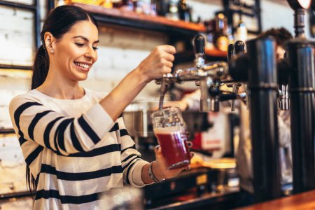 Téléchargez les photos : Femme barman tapping bière dans le bar
. - en image libre de droit