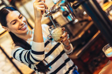 Téléchargez les photos : Femme barman tapping bière dans le bar
. - en image libre de droit