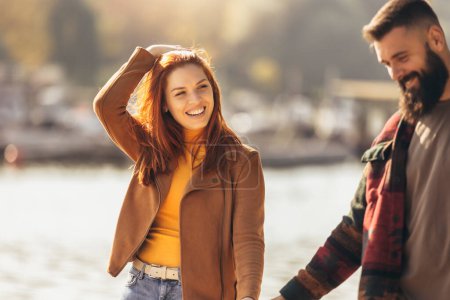 Photo for Happy young couple in love holding hands and walking on coast near river. - Royalty Free Image