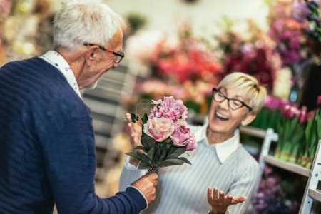 Foto de Romantic middle-aged man giving his beautiful wife flowers - Imagen libre de derechos