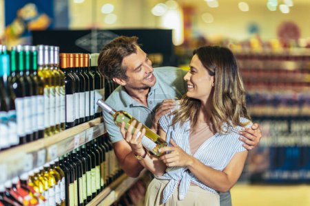 Téléchargez les photos : Smiling couple deciding what wine to buy in grocery store - en image libre de droit